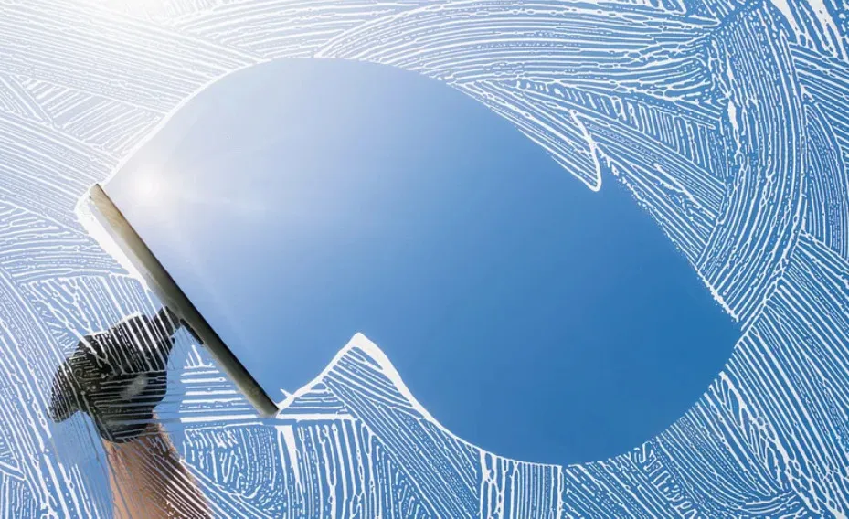 Window cleaning with squeegee, soap patterns on glass.